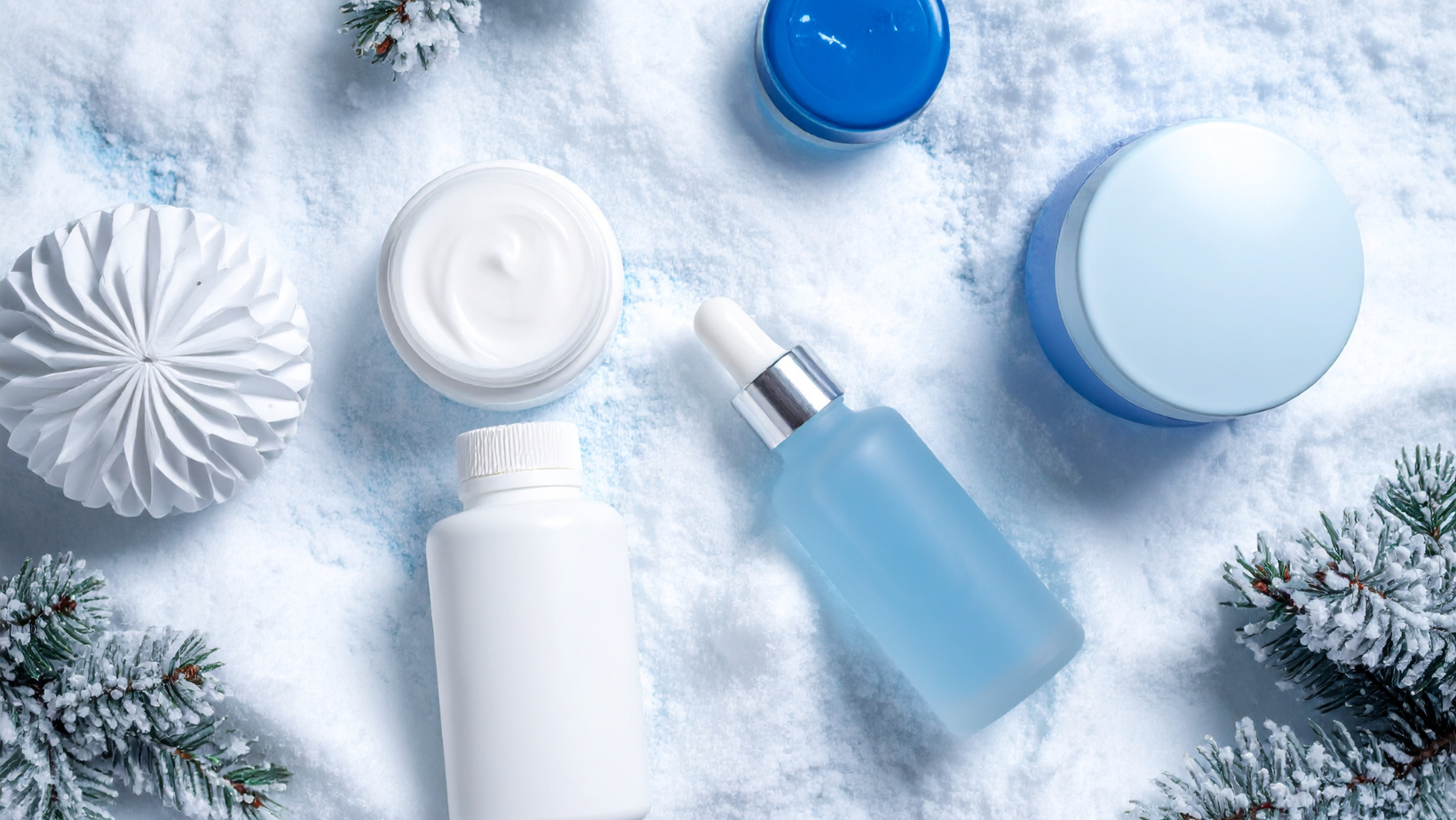 Prodotti skincare invernale su neve: creme e sieri per proteggere viso e mani dal freddo intenso.