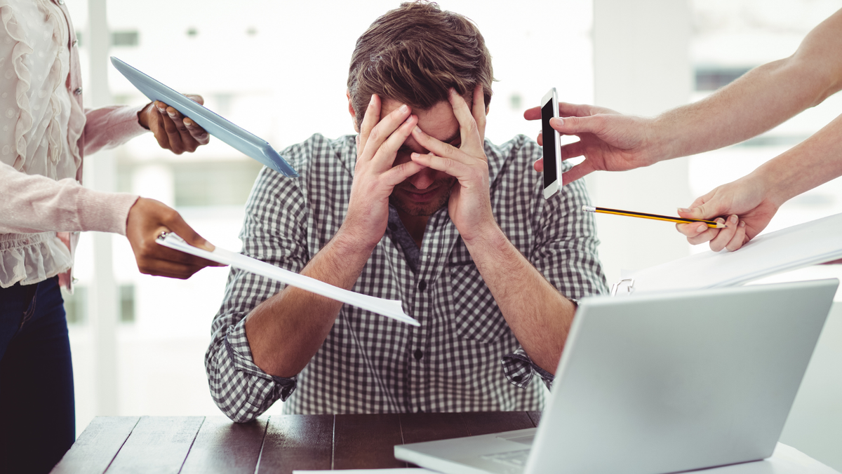 uomo stressato in ufficio con molte cose da fare