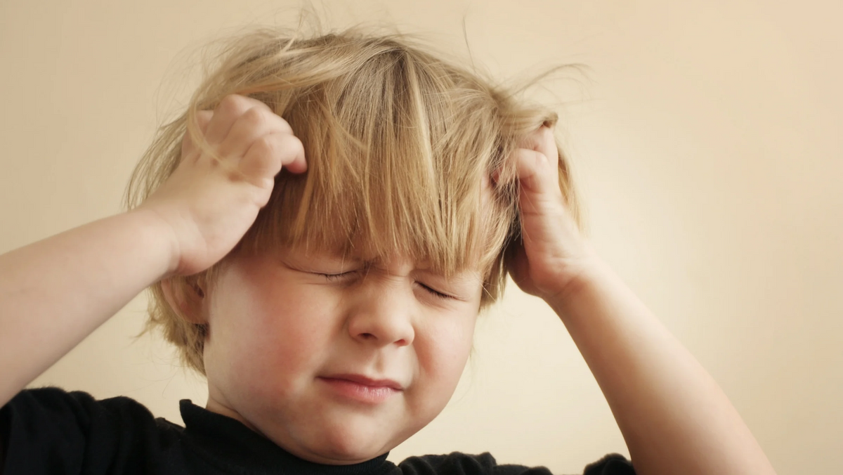 bambino con pidocchi che si gratta la testa